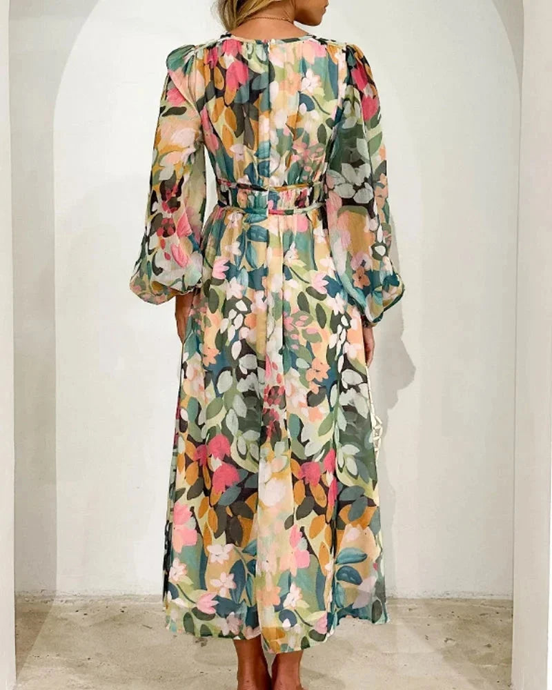 Robe longue fleurie en tissu fluide, col en V et manches longues, avec taille cintrée, parfaite pour un mariage au printemps.