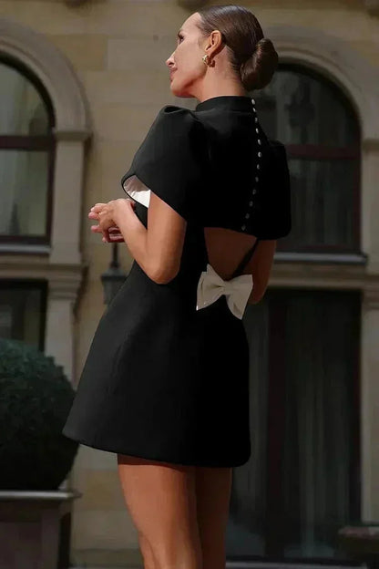 Robe courte ajustée, tissu uni avec manches structurées et volants, idéale pour les cocktails.