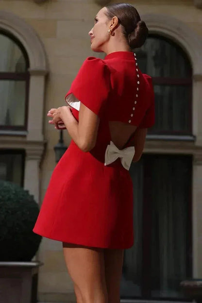 Robe courte unie avec manches structurées et ruffles, silhouette ajustée, parfaite pour les cocktails. Tissu léger et élégant.